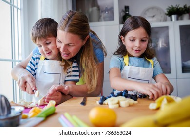 Cute Kids With Mother Preparing A Healthy Fruit Snack In Kitchen 