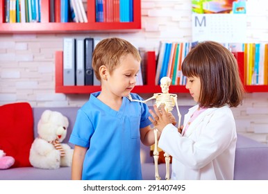 cute kids playing in doctors with toy human skeleton