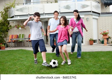 Cute Kids Playing Football With Their Parents At Backyard