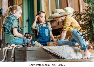 Cute Kids Playing Treasure Hunt With Map On Porch