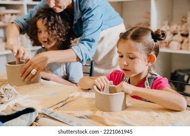 Cute kids sculpting crafts at table in pottery class, working with clay - Powered by Shutterstock