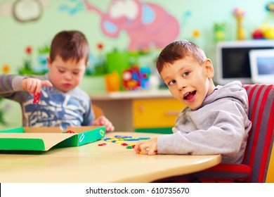 cute kids with special needs playing with developing toys while sitting at the desk in daycare center