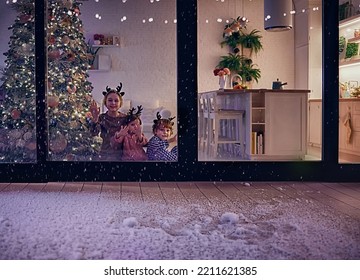 cute kids watching the snow flakes falling on the patio at magical chrismas night, cozy winter holidays - Shutterstock ID 2211621385