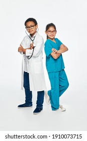 Cute Kids Wearing A Medical Uniform With Arms Crossed On White Background. Two Children Play Medical Staff And Choose A Medical Profession