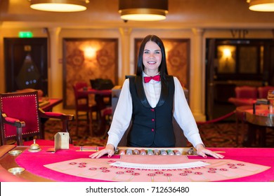 Cute lady casino dealer at poker table.