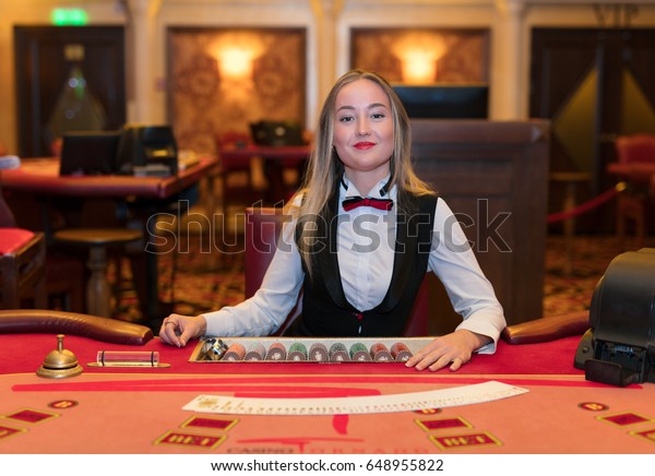 ポーカーテーブルのカジノのかわいい女性のディーラー の写真素材 今すぐ編集