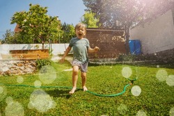 Cute Laughing Handsome Boy Run Around Water Sprinkler In The Garden Lawn On Hot Summer Day