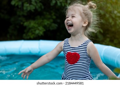 Cute Laughing Little Girl In A Striped Swimsuit With Heart Having Fun In The Pool, Running And Swimming