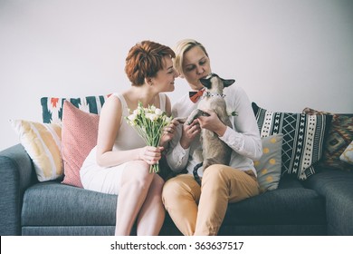 Cute Lesbian Couple In Wedding Outfits Sitting With Their Cat. Gay Marriage Concept. Toned Picture