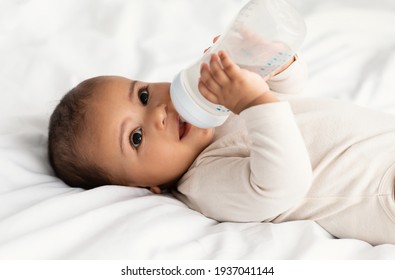 Cute little African American baby drinking from bottle