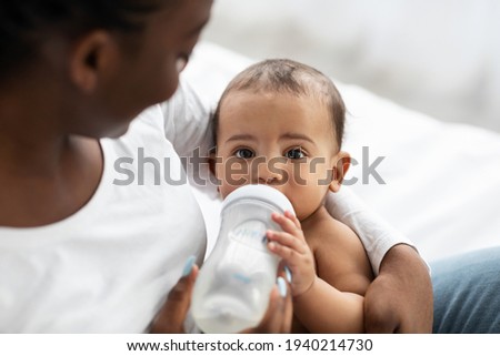 Cute little African American baby drinking from baby bottle