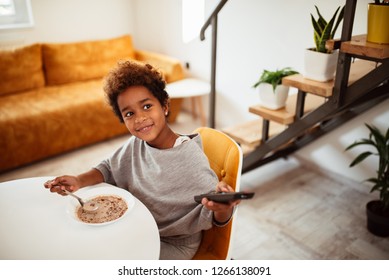 Cute Little African American Girl Eating Healthy Breakfast And Watching Tv.