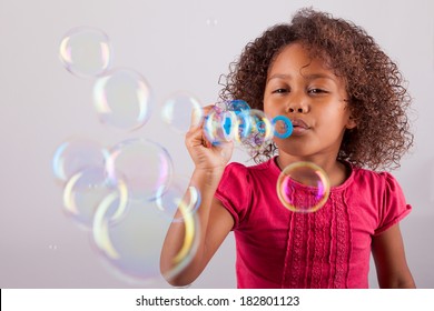 Cute little African American girl blowing soap bubbles - Powered by Shutterstock