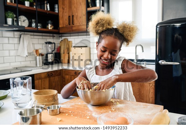 家庭の台所でクッキーを作る かわいい小さなアフリカ系アメリカ人女の子 の写真素材 今すぐ編集