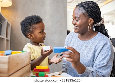 A cute little African child plays with colorful didactic educational toys. His proud mother supports him. Kindergarten teacher with child.