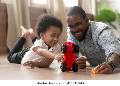 Cute Little African Kid Son Play Toy Cars With Black Dad, Happy Family Small Mixed Race Son And Loving Young Father Babysitter Having Fun Racing On Warm Floor At Home, Family Daddy Child Leisure Game