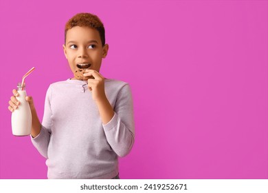 Cute little African-American boy eating cookie with milk on purple background - Powered by Shutterstock