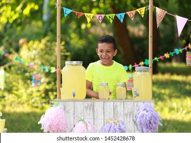 Cute Little African-American Boy At Lemonade Stand In Park. Summer Refreshing Natural Drink