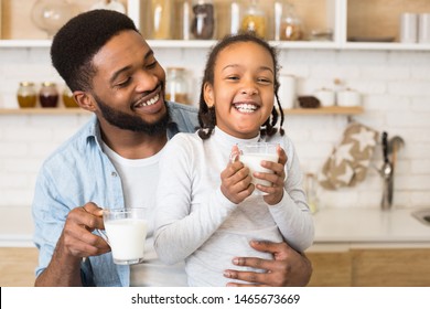 Cute Little Afro Girl And Her Handsome Dad Laughing While Drinking Milk In Kitchen, free space