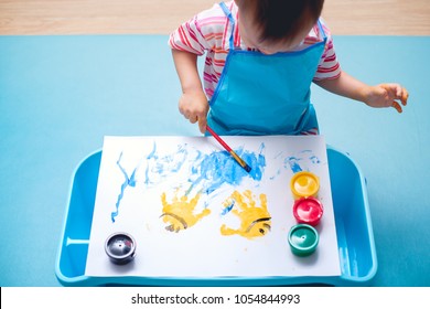 Cute Little Asian 18 Months / 1 Year Old Toddler Baby Boy Child Painting With Paint Brush And Watercolors, Early Child Development, Creative Play For Kids & Toddlers Concept