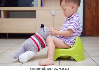 Cute Little Asian 18 Months Old / 1 Year Old Toddler Baby Boy Child Sitting On Potty Playing With His Dog Stuffed Animal Toy. First Friends, Toddlers And Stuffed Animals & Toilet Training Concept