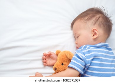 Cute Little Asian 18 Months / 1 Year Old Toddler Boy Child Sleeping / Taking A Nap Under Blanket In Bed While Hugging Teddy Bear, Kid Deep Sleeping, Sweet Dream Concept, Selective Focus At Teddy