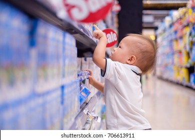 Cute Little Asian 18 Months / 1 Year Old Toddler Baby Boy Child Standing And Choosing Milk Product In Grocery Store / Department Store, Kid Purchasing Milk In Shop