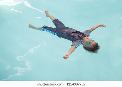 Cute Little Asian 30 Months / 2 Years Old Toddler Baby Boy Learn To Swim In Swimming Class In Thailand, Kid Learn To Float (back Floating) At Indoor Salt Water Pool, Beginner Swimmers Concept