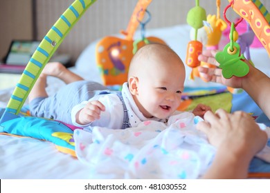 Cute Little Asian 5 - 6 Months Old  Baby Boy Child At Tummy Time On The Play Gym Playing With His Daddy On Bed In Bedroom At Home - Selective Focus