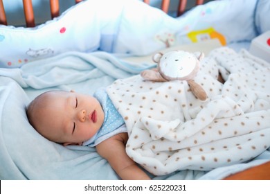 Cute Little Asian 6 Months Old  Baby Boy Child Sleeping In Baby Cot / Crib In Bedroom, Peaceful Kid Lying On Baby Bed While Sleeping, Daytime Sleep Concept / Selective Focus Only At Baby Face