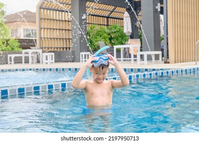 Cute Little Asian 6 Years Old School Boy Child In Swimming Goggles And Snorkel Learning To Swim At Outdoor Pool In Summer Day, Happy Kid Having Fun On Summer Vacation