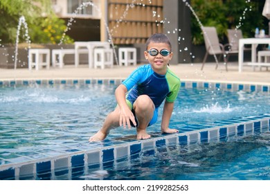 Cute Little Asian 6 Years Old School Boy Child In Swimming Goggles And Swimming Suit Learning To Swim At Outdoor Pool In Summer Day, Happy Kid Having Fun On Summer Vacation