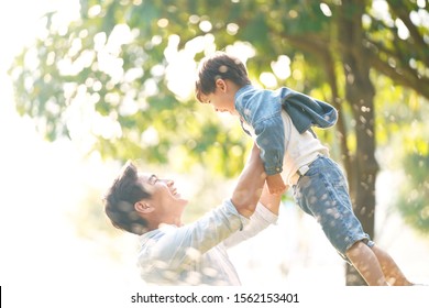 Cute Little Asian Boy Lifted By Father Outdoors In Park