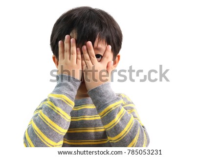 Cute little Asian boy peeks through his fingers, isolated on white background