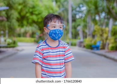 Cute Little Asian Boy Wear Face Mask And Sheild As Protection During The Covid 19 Virus Outbreak. Copy Space.