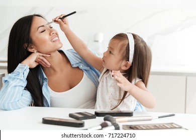 Cute Little Asian Girl Doing Make Up For Her Mother And Having Fun At Home