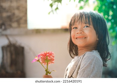 Cute Little Asian Girl Holding A Pink Bouquet. Child Planting Spring Flowers. 