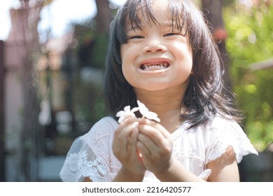 Cute Little Asian Girl Holding A White Bouquet. Child Planting Spring Flowers. 