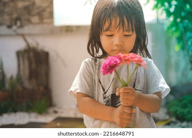 Cute Little Asian Girl Holding A Pink Bouquet. Child Planting Spring Flowers. 