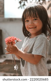 Cute Little Asian Girl Holding A Pink Bouquet. Child Planting Spring Flowers. 