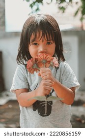 Cute Little Asian Girl Holding A Pink Bouquet. Child Planting Spring Flowers. 