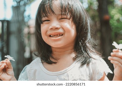 Cute Little Asian Girl Holding A White Bouquet. Child Planting Spring Flowers. 