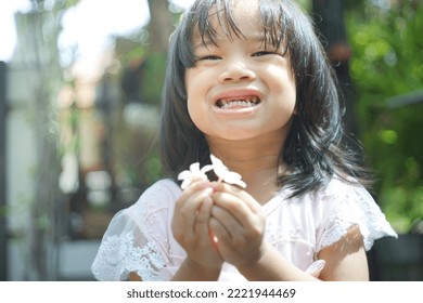 Cute Little Asian Girl Holding A White Bouquet. Child Planting Spring Flowers. 