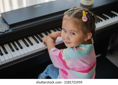 Cute Little Asian Girl Playing Piano At A Music School. Preschool Child Learning To Play Music Instrument. Education, Skills Concept.