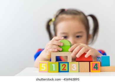 Cute Little Asian Girl Playing Wooden Building Blocks.