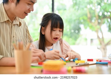 A Cute Little Asian Girl Sculpting Colorful Clay, Making A Cute Flower With Play Dough, Having A Fun Time With Her Dad At Home.