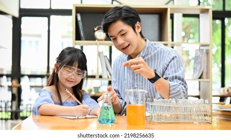 A Cute Little Asian Girl Studying Science At Home With Her Private Tutor. Kids With Scientific Learning Concept