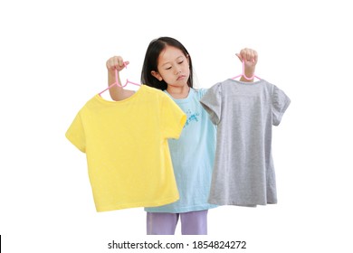 Cute little asian kid girl trying to decide between two shirt on white background