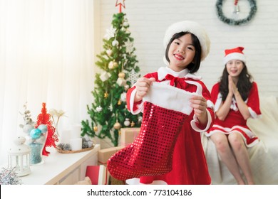 Cute Little Asian Kid Holding A Christmas Stocking Asking For Christmas Gift From Santa Face To The Camera In Winter Holiday Season.