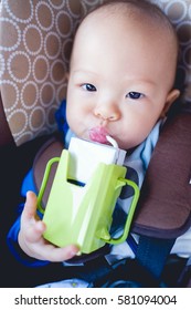 Cute Little Asian Toddler Baby Boy Drinking Milk From A Box With A Straw In Car Seat  In Car